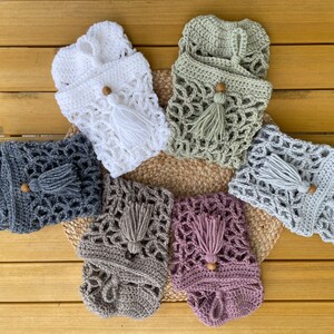 May include: Six crocheted bags with wooden beads and tassels in various colors, including white, gray, green, brown, and pink. The bags are arranged in a circle on a wooden surface.