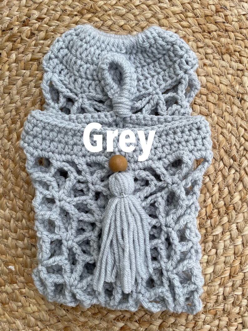 May include: Gray crocheted bag with a wooden bead and tassel. The bag has a geometric pattern and is made with a thick yarn.