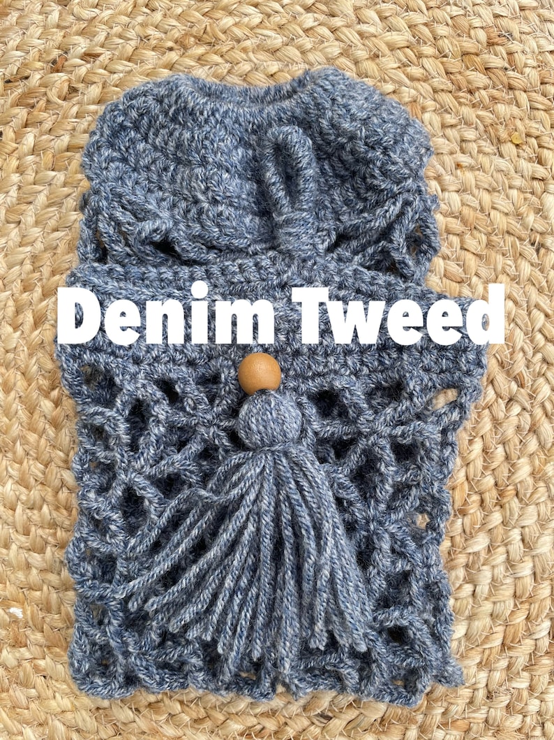 May include: A crocheted bag with a denim tweed texture and a wooden bead tassel. The bag is blue and white and has a woven pattern. The text "Denim Tweed" is written in white letters on a black background.