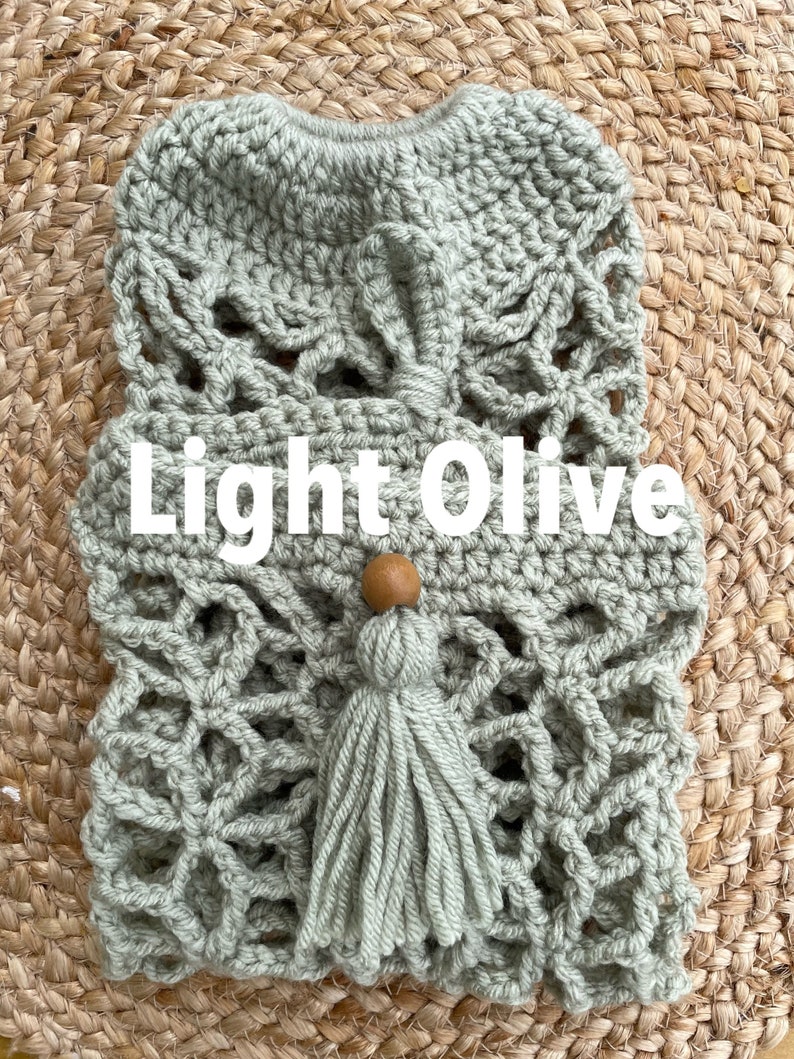 May include: Light olive green crocheted bag with a tassel and wooden bead. The bag has a delicate, intricate design.