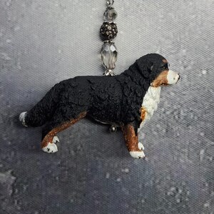 Könnte beinhalten: Ein Schlüsselanhänger mit einem Berner Sennenhund mit einem silbernen Verschluss und Perlenakzenten. Die Hundefigur ist schwarz, weiß und braun, mit detaillierten Merkmalen. Der Schlüsselanhänger ist für Schlüssel oder eine Tasche konzipiert.