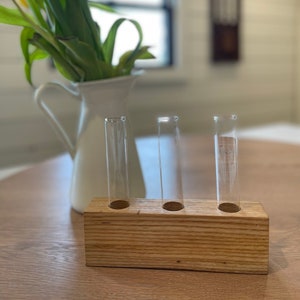 May include: A wooden block with three glass test tubes, perfect for displaying small flower arrangements. The block is made of natural wood with a rustic finish.