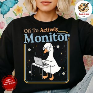 May include: Black sweatshirt with a graphic of a goose wearing glasses and working on a laptop. The text reads "Off To Actively Monitor". The design is framed in a blue and yellow border with small star and flower accents.