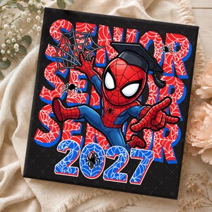 May include: A square black sign featuring a cartoon character in a red and blue suit with a black graduation cap. The background displays the word SENIOR repeated in red with a white spiderweb pattern, and the year 2027 in blue with spiderwebs.