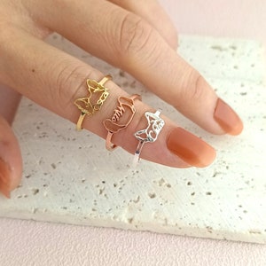 Peut inclure: Trois bagues en or avec des silhouettes d'animaux différentes. Les bagues sont empilées sur un doigt. La bague du haut est en or, la bague du milieu est en or rose et la bague du bas est en argent.