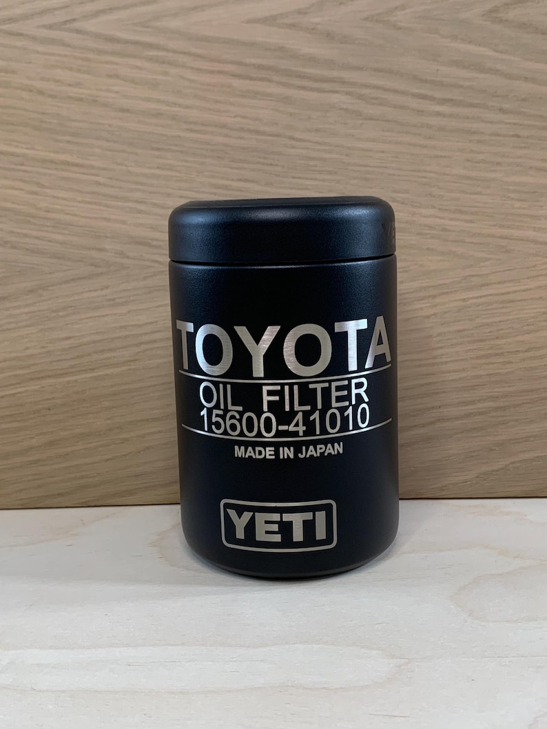 May include: A black YETI oil filter container with the Toyota logo and text "OIL FILTER 15600-41010 MADE IN JAPAN". The container is cylindrical and sits on a light wood surface.