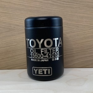 May include: A black YETI oil filter container for Toyota vehicles. The container has the Toyota logo and "OIL FILTER 15600-41010" printed in silver. The text "MADE IN JAPAN" and the YETI logo are also visible.
