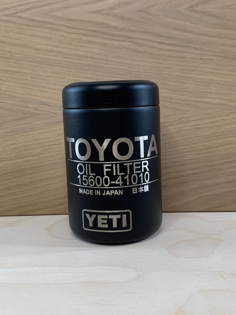 May include: A black YETI oil filter container for Toyota vehicles. The container has the Toyota logo and "OIL FILTER 15600-41010" printed in silver. The text "MADE IN JAPAN" and the YETI logo are also visible.