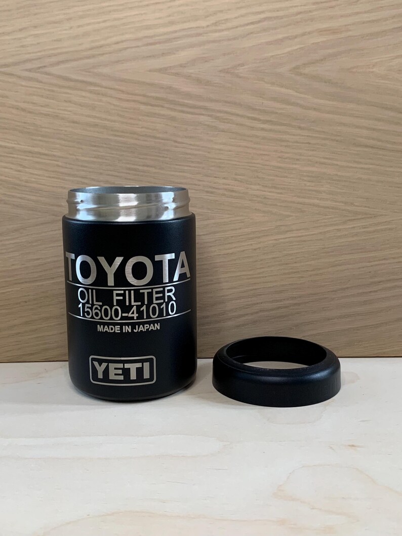 May include: Black YETI tumbler with a silver rim and a separate black ring. The tumbler features the word "TOYOTA" and "OIL FILTER 15600-41010" in white text. The text "MADE IN JAPAN" is also visible.
