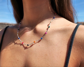 May include: A silver chain necklace with colorful square beads. The beads are in shades of pink, blue, green, orange, and black.