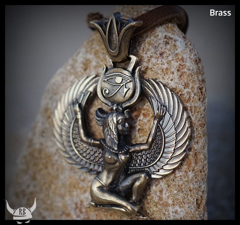 Puede incluir: Un colgante de lat&oacute;n que representa a la diosa egipcia Isis con las alas extendidas. El colgante incluye el s&iacute;mbolo del Ojo de Horus y un dise&ntilde;o de flor de loto.