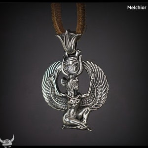 Puede incluir: Collar con colgante de plata que presenta una representaci&oacute;n detallada de la diosa egipcia Isis con las alas extendidas, sosteniendo el s&iacute;mbolo del Ojo de Horus sobre su cabeza. El colgante est&aacute; unido a un cord&oacute;n de cuero marr&oacute;n.