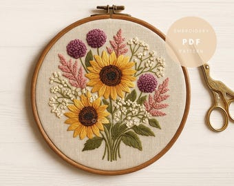 May include: Embroidered floral design featuring two sunflowers, purple pom-pom flowers, and pink and white foliage. The embroidery is set in a wooden hoop. A pair of gold scissors is on the right. The text "EMBROIDERY PDF PATTERN" is on the right.