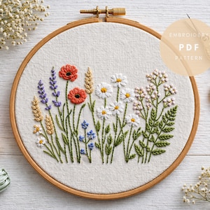 Può includere: Un telaio da ricamo circolare con un motivo floreale, con papaveri rossi, lavanda e margherite. Il ricamo è su tessuto color crema, tenuto in un telaio di legno. Il testo "Embroidery PDF Pattern" è visibile.
