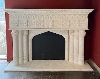 May include: A white marble fireplace mantel with a black fireplace opening. The mantel has intricate carvings and a decorative design.