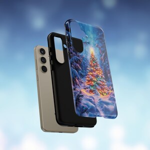 May include: A smartphone and two phone cases. One case features a winter scene with a decorated Christmas tree. The other case is black. The phone is a light gold color.