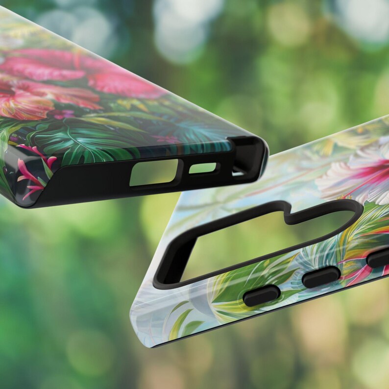 May include: Two phone cases with a tropical floral design. One case features a vibrant mix of pink flowers and green leaves, while the other showcases a similar pattern with a lighter color palette. Both cases have black edges.