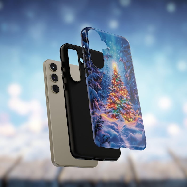 May include: A smartphone with a protective case featuring a winter scene with a decorated Christmas tree. The case has a clear, glossy finish, and the phone is a light beige color. The case is black on the inside.