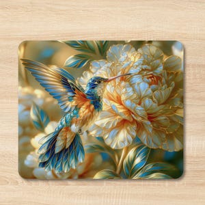 May include: A rectangular mouse pad featuring a vibrant illustration of a hummingbird with blue, gold, and orange feathers hovering near a large, layered cream and gold flower with blue-tinted petals and green leaves in the background.