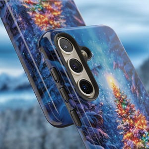 May include: A blue phone case featuring a winter forest scene with a decorated Christmas tree. The case has a glossy finish and a black border, with a camera and button details visible. The design includes snow-covered trees and a starry sky.