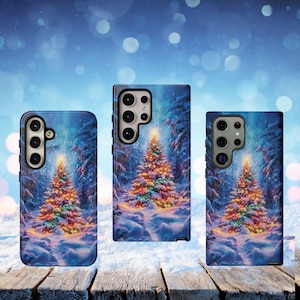 May include: Three phone cases with a winter scene featuring a decorated Christmas tree. The cases have a blue background with a snowy forest and a brightly lit tree. The cases are on a wooden surface.