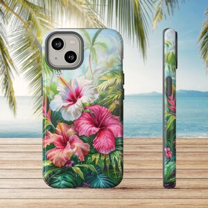 May include: A phone case featuring a vibrant tropical floral design. The case showcases three hibiscus flowers in shades of pink and white, surrounded by lush green foliage. The side view of the case displays a continuation of the tropical theme.