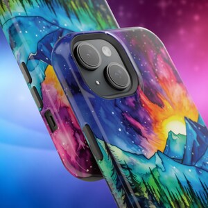 May include: A phone case featuring a watercolour design of a mountain range with a sunset and aurora borealis in the sky. The case is made from hard plastic and has a clear back.