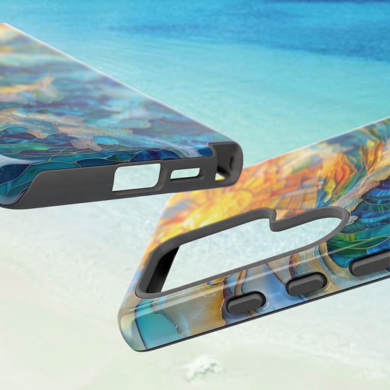 May include: Two phone cases with a colorful abstract design in shades of blue, gold, and teal. The cases have a black border and cutouts for the phone's features. The background is a blurred image of a beach and ocean.
