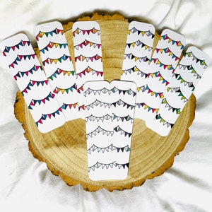 May include: A set of eight colourful bookmark designs featuring a string of flags. Each bookmark is printed on white cardstock and features a different colour scheme of flags.