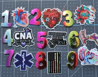 May include: Nine colorful stickers with different designs, including a heart, a star, and a human ear. Each sticker has a number from 1 to 9 on it. The stickers are on a gray background.