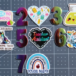 May include: Seven colorful holographic stickers with different school-themed designs. The stickers feature numbers 1 through 7, with each number paired with a different design. The designs include a heart with school supplies, a beaker with a smiley face, a dinosaur with the text "Teachersaurus", a rainbow with the text "School Nurse", a teacher assistant heart, and a lunch squad design.