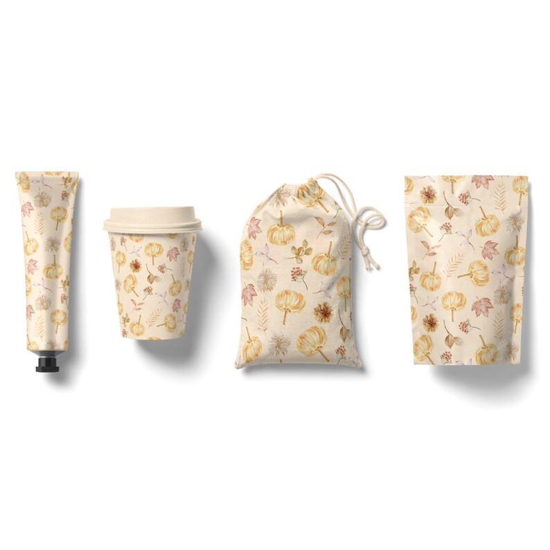 May include: A set of four fall-themed products featuring a cream-colored background with a repeating pattern of small pumpkins, leaves, and flowers. The set includes a tube of hand cream, a coffee cup, a small drawstring bag, and a pouch.