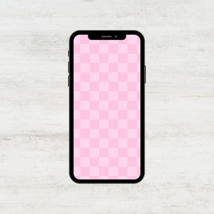 May include: A black smartphone with a pink checkered screen on a white wooden background.