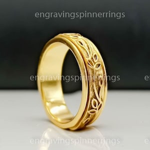 May include: A gold spinning band ring with a floral design. The ring is made of metal and has a smooth finish.