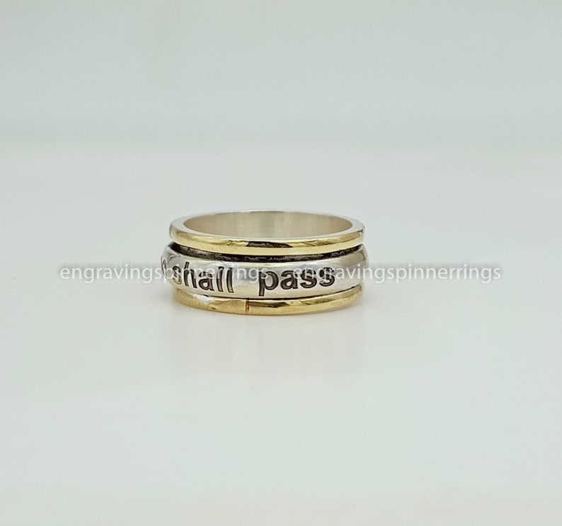 K&ouml;nnte beinhalten: Ein drehbarer Ring aus Silber und Gold mit der Gravur "This too shall pass".