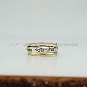 K&ouml;nnte beinhalten: Ein drehbarer Ring aus Silber und Gold mit der Gravur "this too shall".