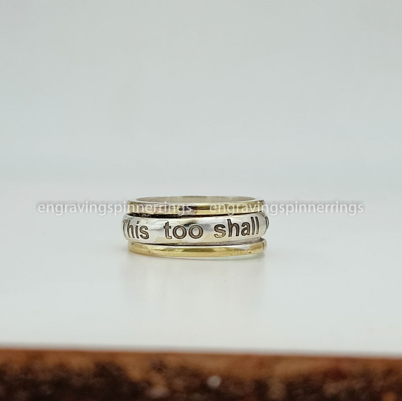 K&ouml;nnte beinhalten: Ein drehbarer Ring aus Silber und Gold mit der Gravur "this too shall".