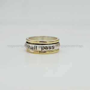 K&ouml;nnte beinhalten: Ein drehbarer Ring aus Silber und Gold mit der Gravur "This too shall pass".