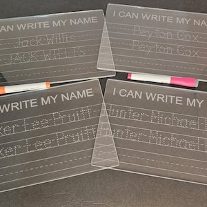 May include: Four clear plastic dry-erase boards with dotted lines for tracing names. The boards have the text "I can write my name" printed on them. The names on the boards are Jack Willis, Peyton Cox, Parker Lee Pruett, and Hunter Michael Lemer.