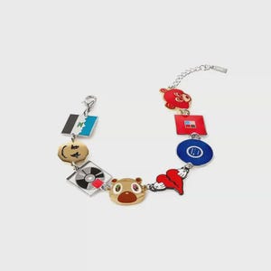 May include: A silver-tone chain bracelet featuring multiple colorful enamel charms, including a brown bear head, a red heart, a blue circle, a red square, a black and white vinyl record, a gold smiley face, and a blue, black, and white flag-like square.