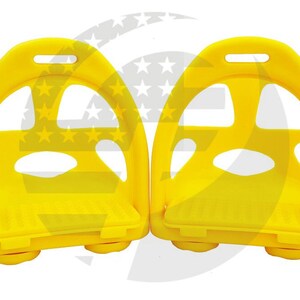 Pode incluir: Dois estribos de pl&aacute;stico amarelo brilhante com uma superf&iacute;cie texturizada e uma parte superior arredondada. Os estribos t&ecirc;m um furo na parte superior e um pequeno l&aacute;bio na parte inferior.