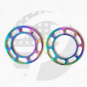 May include: Two iridescent metal rings with multiple oval cutouts. The rings are a rainbow of colors, including purple, blue, green, and gold.