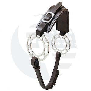 May include: A horse bit with a dark brown leather headstall and straps. The bit features two circular, silver-colored rings with decorative cutouts. A silver buckle secures the headstall.