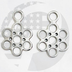 May include: Two polished metal flower-shaped objects with multiple circular openings. Each has a central ring and six surrounding rings, connected by curved lines. The top has a single ring. The objects are symmetrical and appear to be decorative or functional.