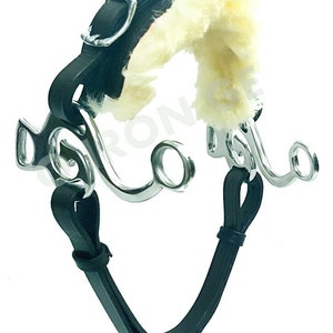 May include: A black leather horse bit with a white sheepskin covering. The bit has a silver mouthpiece with two rings on each side.