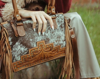 El bolso Zebedee Concealed Carry de Haute Southern Hyde by Beth Marie Exclusive, con flecos de piel de vaca, es un exclusivo bolso de mano de piel de vaca.