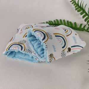Könnte beinhalten: Ein Paar blaue und weiße Kinderwagenriemen mit einem Regenbogenmuster. Die Riemen sind mit weichem blauen Fleece gefüttert.