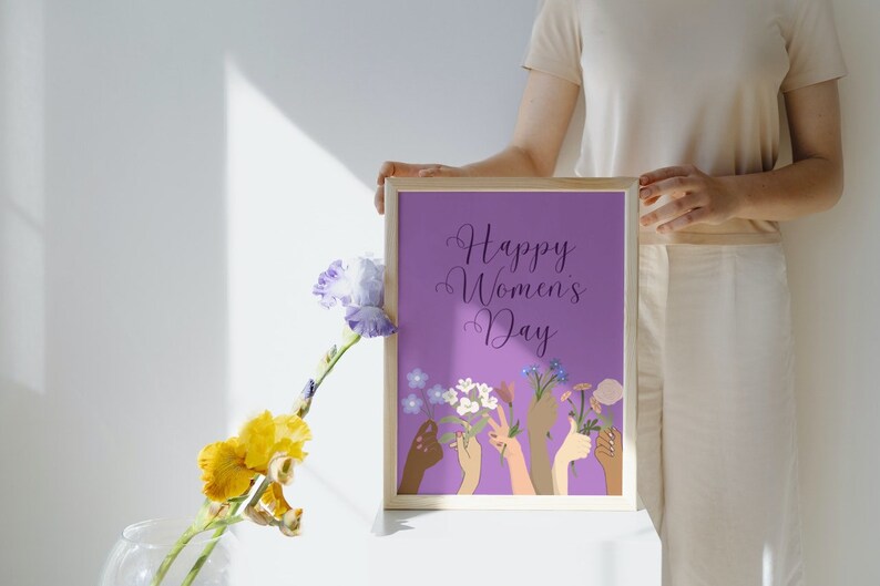 May include: A purple framed print with the text "Happy Women's Day" and an illustration of hands holding flowers.
