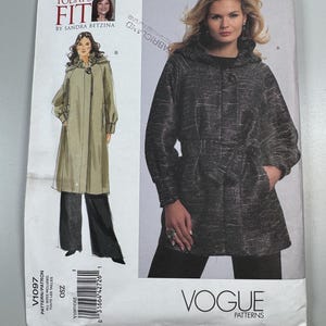 May include: A white ceramic mug with a black handle and the text "But First, Coffee" in a bold, black font. The mug is set against a blurred background, suggesting a cozy setting.