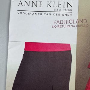 Puede incluir: Un patrón de Anne Klein New York Vogue American Designer. La imagen muestra una falda negra con una cinturilla roja. También se ve el texto "Fabricland" y "No Return No Refund".